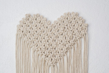 Heart-shaped macrame pattern with fringes on white background