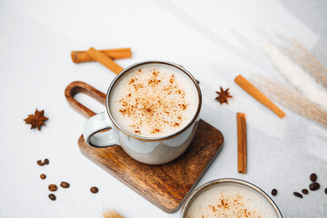 Warm creamy drink with cinnamon spice in mug, coffee beans and star anise