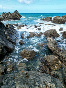 Rocks and sea off the north Devin coast at heartland with waves calmly breaking against the shore