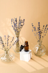Amber dropper bottle with glass pipette placed among lavender flowers in glass vases