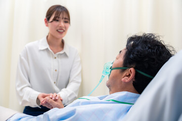 Obraz premium 人工呼吸器をつけた男性と病院に駆けつけた家族