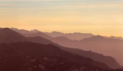 Panoramic view of the silhouettes of mountains bathed in sunset light in marsala tones