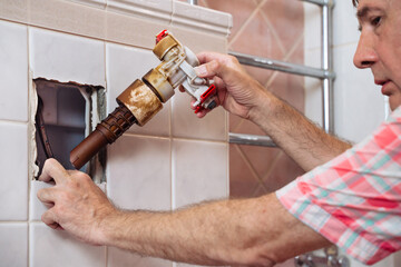 A person is actively changing a fill valve in a bathroom, ensuring proper water flow and functionality