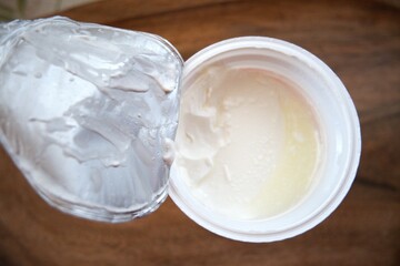 Close-up of sour cream in an open plastic container, isolated for food and dairy concepts.