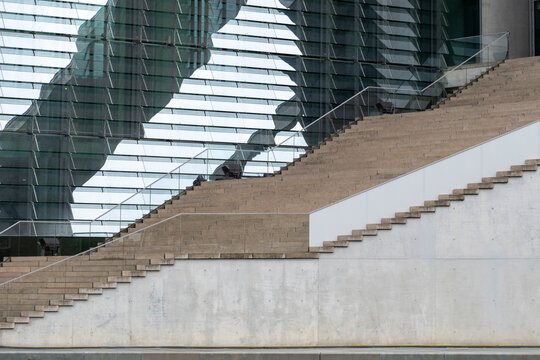 Modern staircase and layered glass facade with concrete base, architectural rhythm combining transparency, structure and urban progress in contemporary construction design