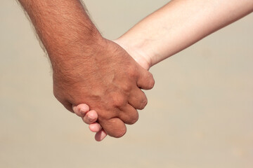 two hands, male and female or child's, with intertwined fingers. Close-up
