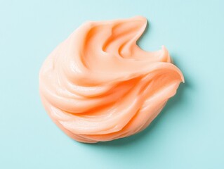 Creamy Peach Colored Swirl of Smooth Facial Product on Soft Blue Background for Skin Care and Beauty Concepts