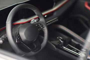 Closeup of a modern car steering wheel with control buttons for technology and convenience