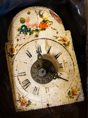 A antique wall clock with worn painted floral motif