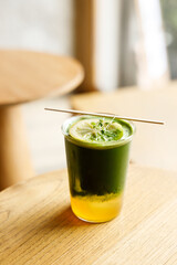 Creation beverage of fresh matcha tea, green tea and lemon juice on wooden table by the window.