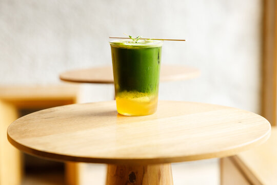 Creation beverage of fresh matcha tea, green tea and lemon juice on wooden table by the window.