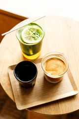 Cup of milk dirty coffee and Creation beverage of fresh matcha tea, green tea and lemon juice on wooden table by the window.