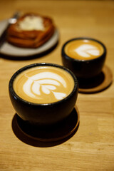 Cup of hot milk latte coffee and Mushroom danish pastry on table.
