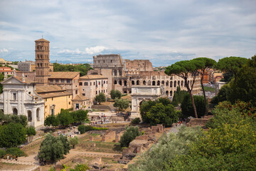 Fototapeta premium Panoramic Daytime View of Roman Forum with Arch of Titus, Colosseum, and Historic Churches in Rome, Italy