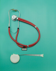 red stethoscope and measuring tape on green Background, Space for Text, Space for Logo