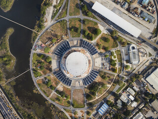Aerial view of a stadium surrounded by lush greenery and winding paths, reflecting the sun's golden rays, New Orleans, Louisiana, United States.