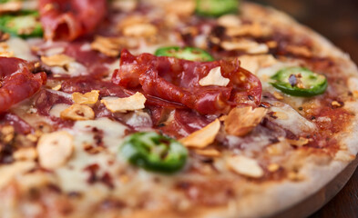 Pizza with salami, mozzarella cheese and jalapeno pepper. Wooden background. Soft focus.	
