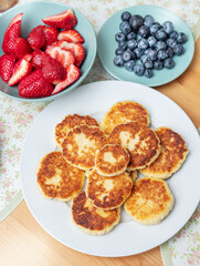 Syrniki or fried cottage cheese pancakes on white plate on the table.