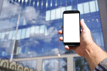 Businessman holding smartphone with blank screen in front of office building