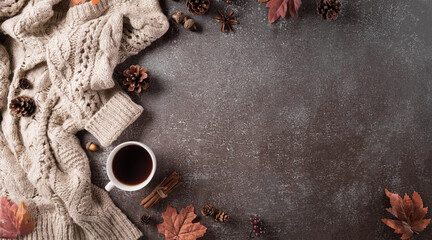 Autumn composition. A cup of coffee, cotton flowers, autumn leaves and sweater on dark stone background. Flat lay, top view with copy space.