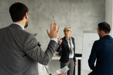 Business lecture with a male participant raising his hand to answer a question
