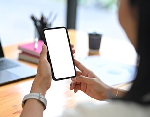 Person holding a blank smartphone at a desk