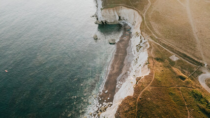A beautiful view of the ocean and a rocky shoreline. The water is calm and the sky is clear