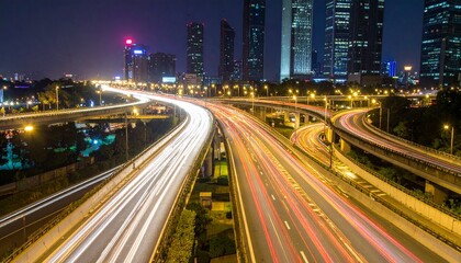 Fototapeta premium Night cityscape view of a complex highway system with light trails from moving vehicles.