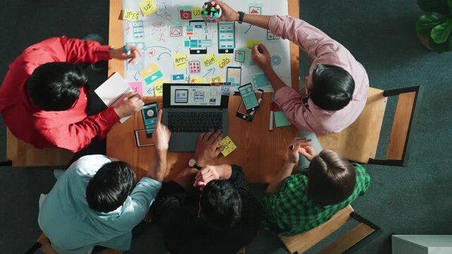 Top view of smart creative project manager using laptop working on Ux Ui design for mobile phone interface while marketing team designing software program by using brainstorming mind map. Convocation.