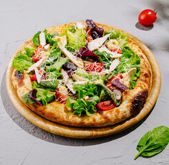 Freshly made salad pizza with colorful toppings and herbs on wooden board