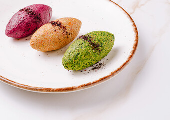 Trio of colorful gourmet spreads served in quenelle shape on a ceramic plate. Elegant restaurant presentation with beet, herb, and vegetable pate or mousse.