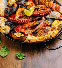 Seafood plate with octopus, shrimp, fish, and lime on wood table