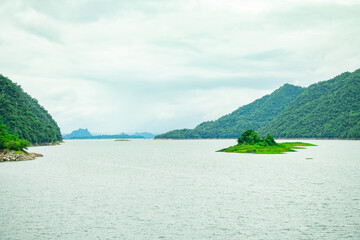 A wide landscape view of a hydroelectric dam reservoir surrounded by lush green mountains and dense forest, symbolizing clean energy, renewable power, and sustainable natural resource management.