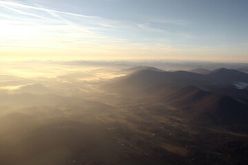 Sunlit mountain range, valley mist, aerial view