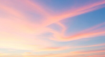 Fototapeta premium Pastel pink and orange clouds drift across a soft blue sky