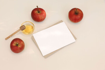 Flat lay of red apples, honey, wooden dipper. Blank greeting card, invitation mockup on white table background in sunlight. Bright seasonal still life. Autumn, Rosh Hashanah, Thanksgiving holiday. Top