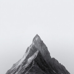 Minimalist monochrome image of a stark mountain peak piercing a misty sky. Symbolizing ambition, challenge, and overcoming obstacles. Great for motivational content, or travel themes.