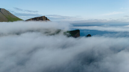 Misty landscapes over rugged cliffs in the serene Faroe Islands at sunrise