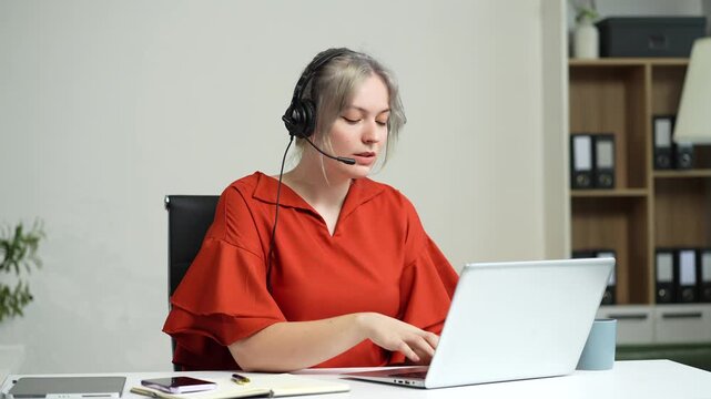 Friendly smiling female call-center agent with headset working on support hotline in office.