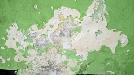 Close up of old green painted wall with peeling paint and weathered texture. Grunge background of cracked and damaged surface, showing layers of blue paint underneath. Abstract vintage wall texture
