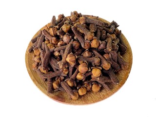 Dried clove spices in a wooden bowl isolated on white background. Aromatic dried clove flower buds. Dried clove spice.