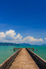 Fototapeta premium Tropical bay with limestone cliffs and green water under a bright blue sky, lush vegetation in the foreground. 