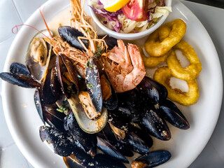 Dish with seafood such as mussels, shrimp and calamari rings accompanied by salad