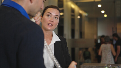 A hotel receptionist assisting with check-in and check-out, smiling and eager