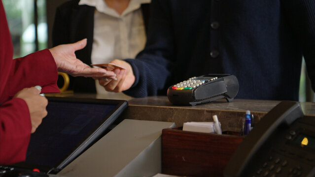 Customer making payment at hotel reception using credit card terminal - Powered by Adobe
