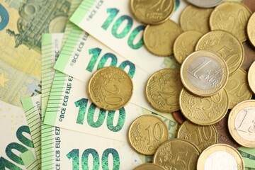 Big amount of euro cent coins lies on hundred euro bills banknotes
