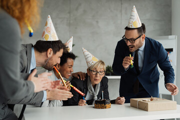 Group of business people is celebrating the birthday of a middle-aged female colleague in modern office