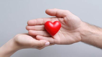 Obraz premium A red heart is held gently between two hands against a neutral backdrop, symbolizing love and care.
