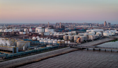 Obraz premium Aerial view of a large coastal oil refinery with storage tanks at dusk