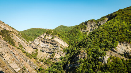 Dramatic rock folds and lush green slopes surround the Armazi Fortress site near Mtskheta, Georgia. A vivid landscape shaped by both nature and history